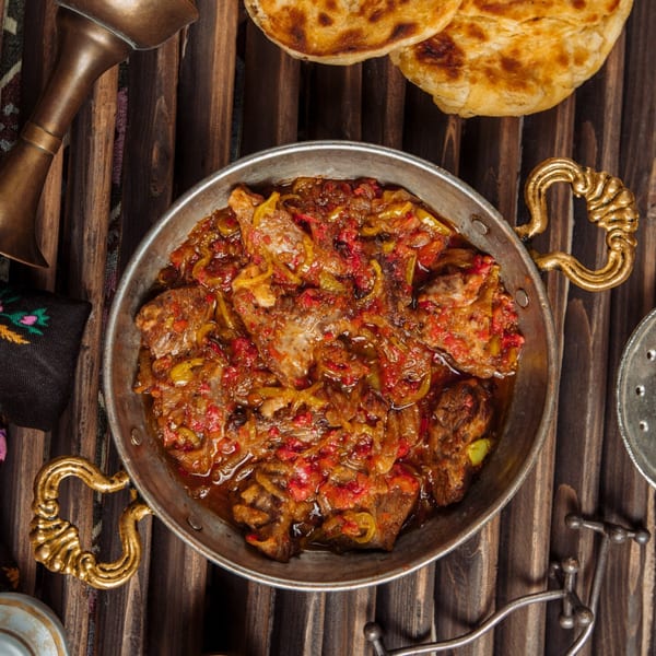 Curry Nation's Indian takeaway, a metal pan filled with meat and vegetable curry, with naan bread.