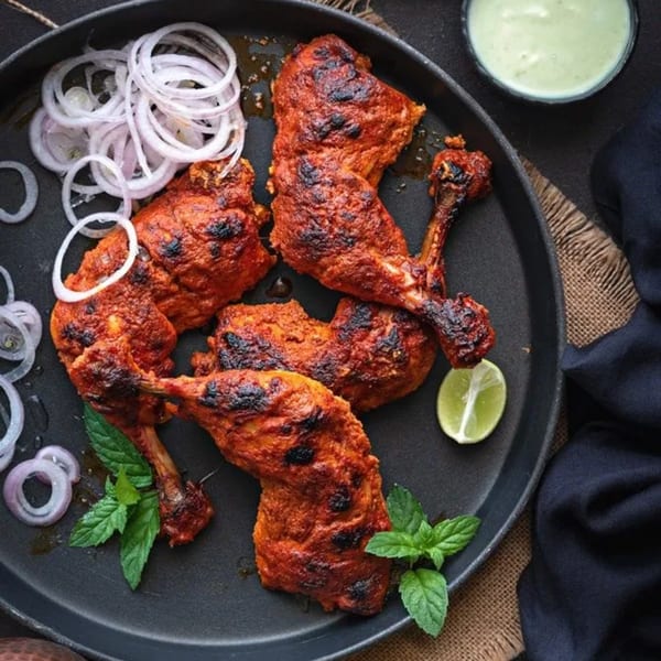 Curry Nation's Tandoori Chicken with sliced onions, mint, lime, and a side of green chutney.