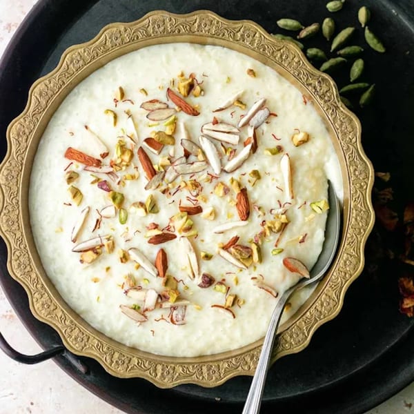Creamy Indian rice pudding (kheer) in a gold bowl, topped with almonds, pistachios, and saffron.