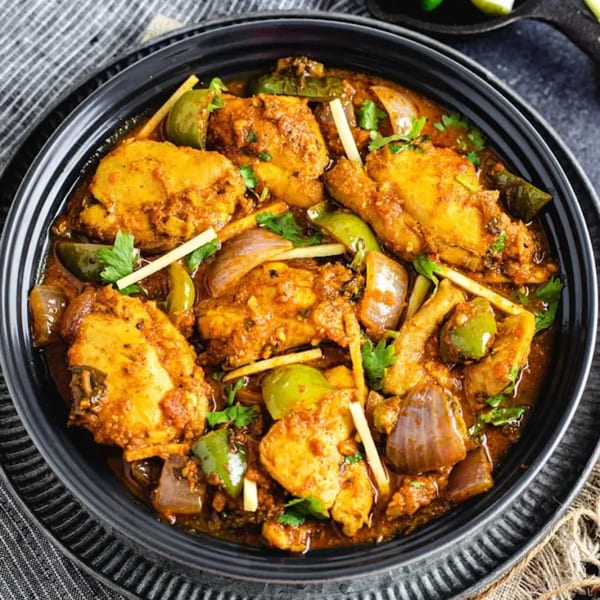 Curry Nation's chicken curry with bell peppers, onions, and cilantro in a black bowl.